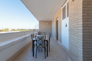 A balcony with a table and chairs, a white door, and a brick wall. - Casa Titty (Rome)
