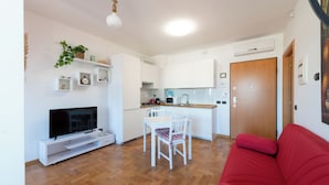 Ein kompakter Wohnraum mit Küche, Essbereich und einem roten Sofa.