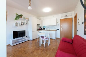 Ein kompakter Wohnraum mit Küche, Essbereich und einem roten Sofa.