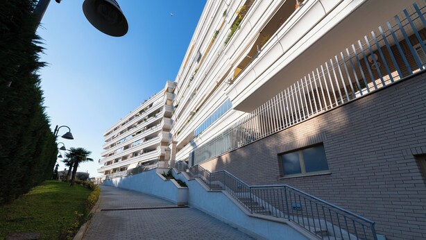 Ein mehrstöckiges Gebäude mit Ziegelaußenwand und einer Treppe, die zu den oberen Stockwerken führt, vor einem wolkenlosen Himmel.