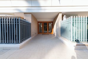 A building entrance with a tiled floor, a wooden door, and metal gates. - Casa Titty (Rome)