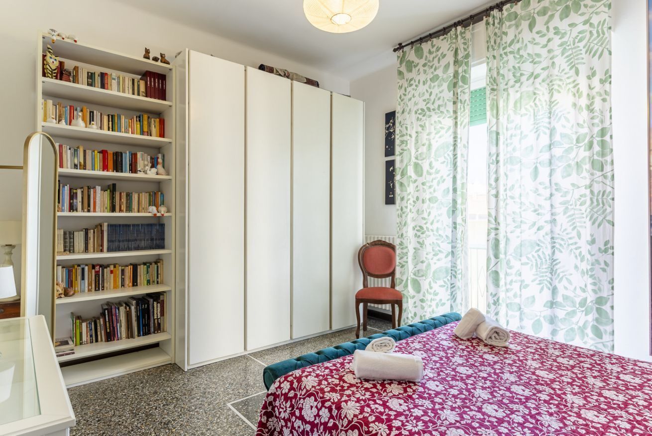 Ein Schlafzimmer mit Bett, Bücherregal, Sessel und Kleiderschrank.