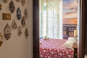 A bedroom with a bed, a nightstand, a lamp, and a view of the sea through curtains. - Spacious 80 sqm apartment with a balcony, comfortably accommodating up to 4 people, located on the third floor of a building with an elevator. The property is located in the charming Centro neighborhood, in the heart of Livorno's nightlife, just steps fr (Livorno)
