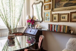 A room with a glass table, a chair, a bookshelf, and a mirror. - GuestHost - Library Appartment - Teresa's House (Livorno)