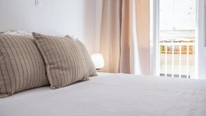 A hotel room with a bed, curtains, and a view of a building outside. - Charming Couples' Apartment in Zakynthos Town (Zakinthos)