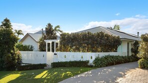 A residential house with a white fence, a covered porch, and a well-maintained lawn.