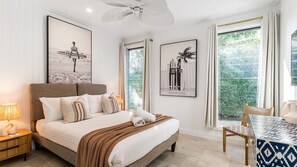 Ein Schlafzimmer mit einem Bett, einem Nachttisch, einem Tisch mit Stuhl und zwei gerahmten Bildern an der Wand.