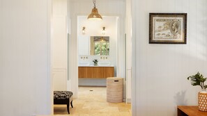 A hallway leading to a bathroom with a wooden vanity, a hanging light fixture, and a framed postage stamp on the wall. - Welcome to Pineapple House, a relaxed take on luxury in the heart of Byron Bay, where colonial plant (Byron Bay)