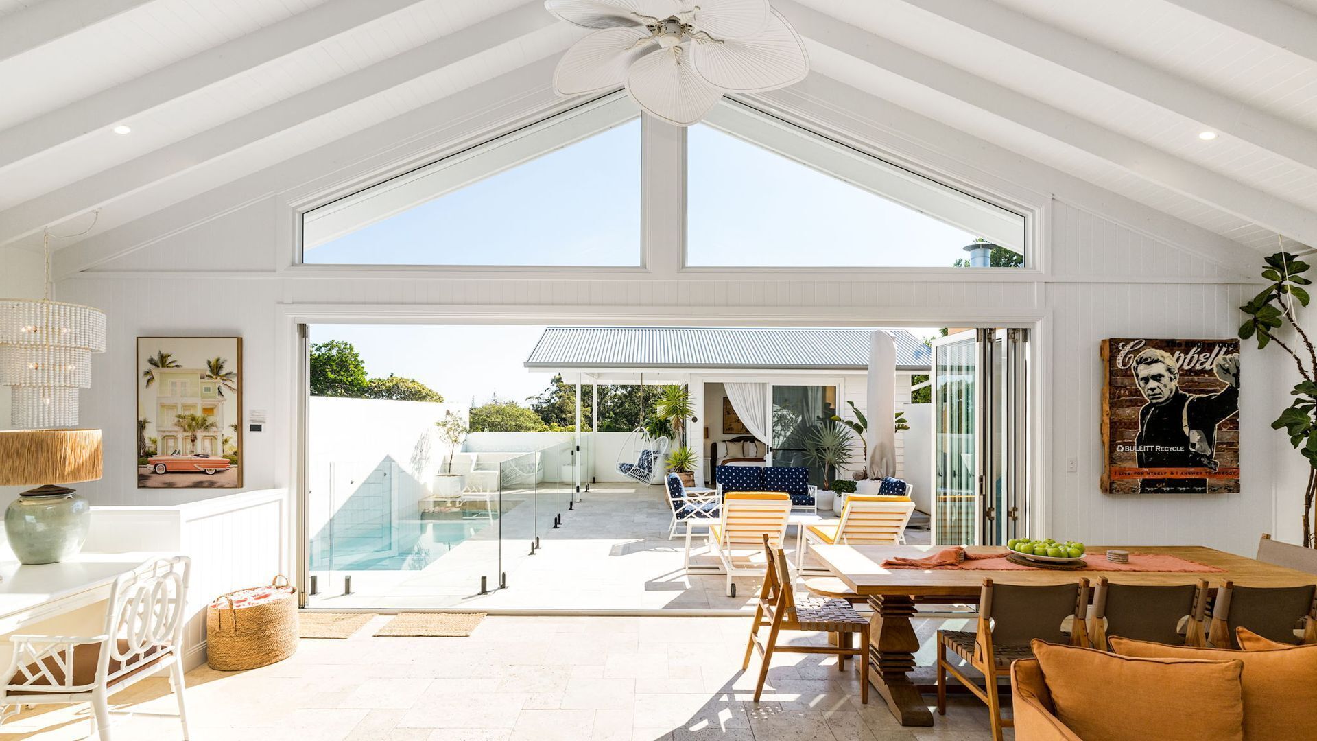 Un espace de vie à aire ouverte comprenant une salle à manger avec table et chaises, et donnant sur une piscine et un espace de détente extérieur.