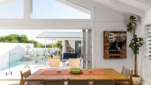 Zona pranzo con vista piscina, una poltrona sospesa e un poster appeso al muro.