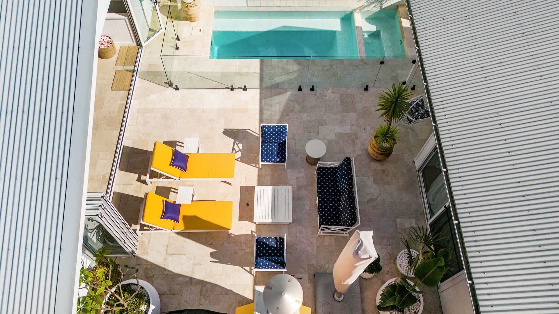 An aerial view of a rooftop pool area with lounge chairs and a small table.