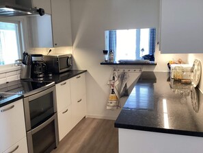 A modern kitchen with a microwave, coffee maker, and a window with curtains.