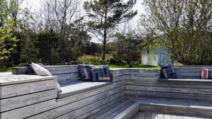 A wooden deck with built-in seating and a small table. - 4 Star Holiday Home in Hamburgsund (Hamburgsund)
