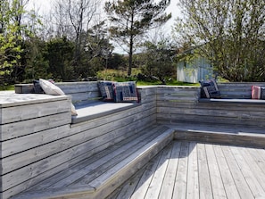Una terraza de madera con asientos integrados y una pequeña mesa.