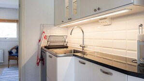 A compact kitchen with white cabinets, a black countertop, and a stainless steel sink. - 4 Star Holiday Home in Hamburgsund (Hamburgsund)