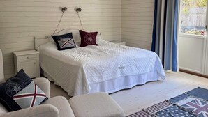 A bedroom with a bed, nightstands, a chair, and a view through a window. - 4 Star Holiday Home in Hamburgsund (Hamburgsund)