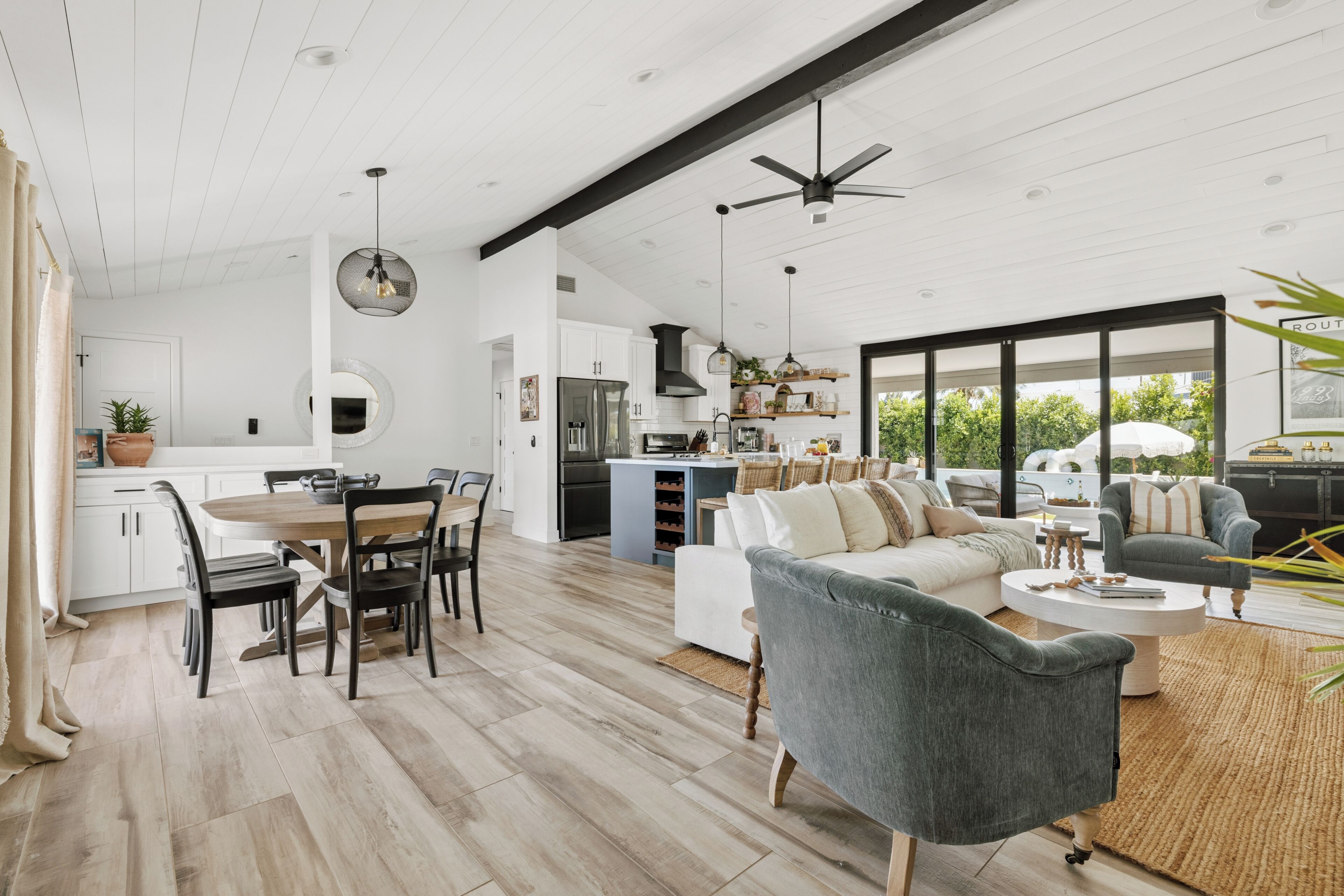 A spacious living area with a dining table, sofas, and a kitchen in the background.