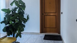 Ein Flur mit einer Holztür, einem Blumentopf und einem Fliesenboden.