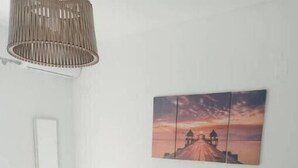 Ein modernes Badezimmer mit einem weißen Waschtisch, einer hängenden Leuchte und einem Sonnenuntergangsbild an der Wand.