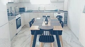 Eine moderne Küche mit weißen Schränken, einem Esstisch mit Stühlen und einem eingebauten Backofen.