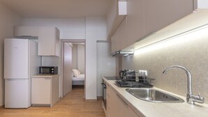 Een compacte keuken met een magnetron, kookplaat, spoelbak en een klein eethoekje.