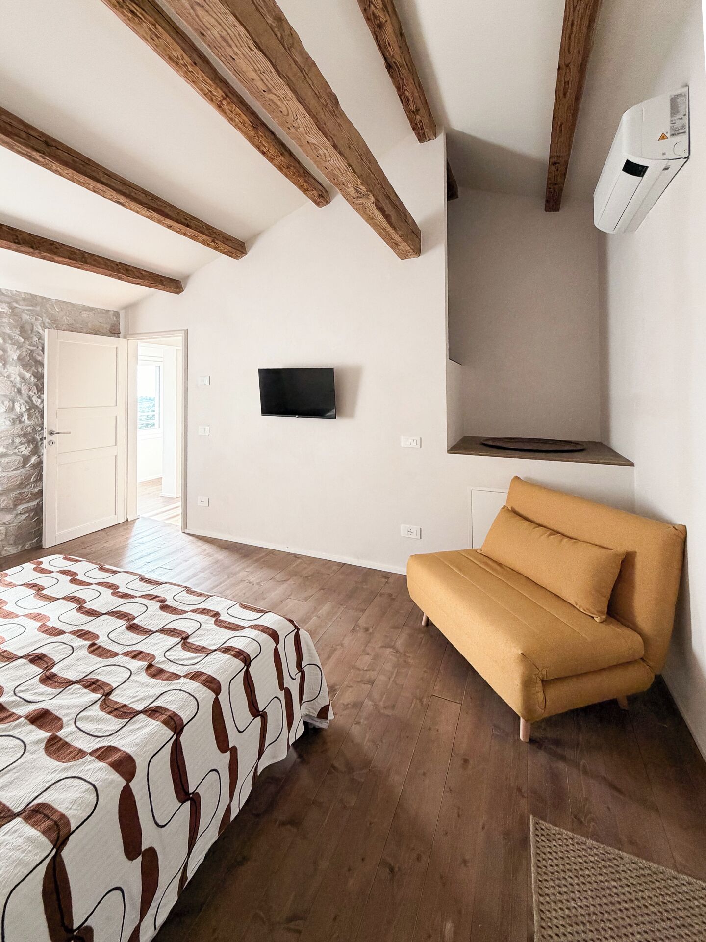 Ein Schlafzimmer mit einem Bett, einem Schlafsofa, einem Fernseher und einem Kamin.