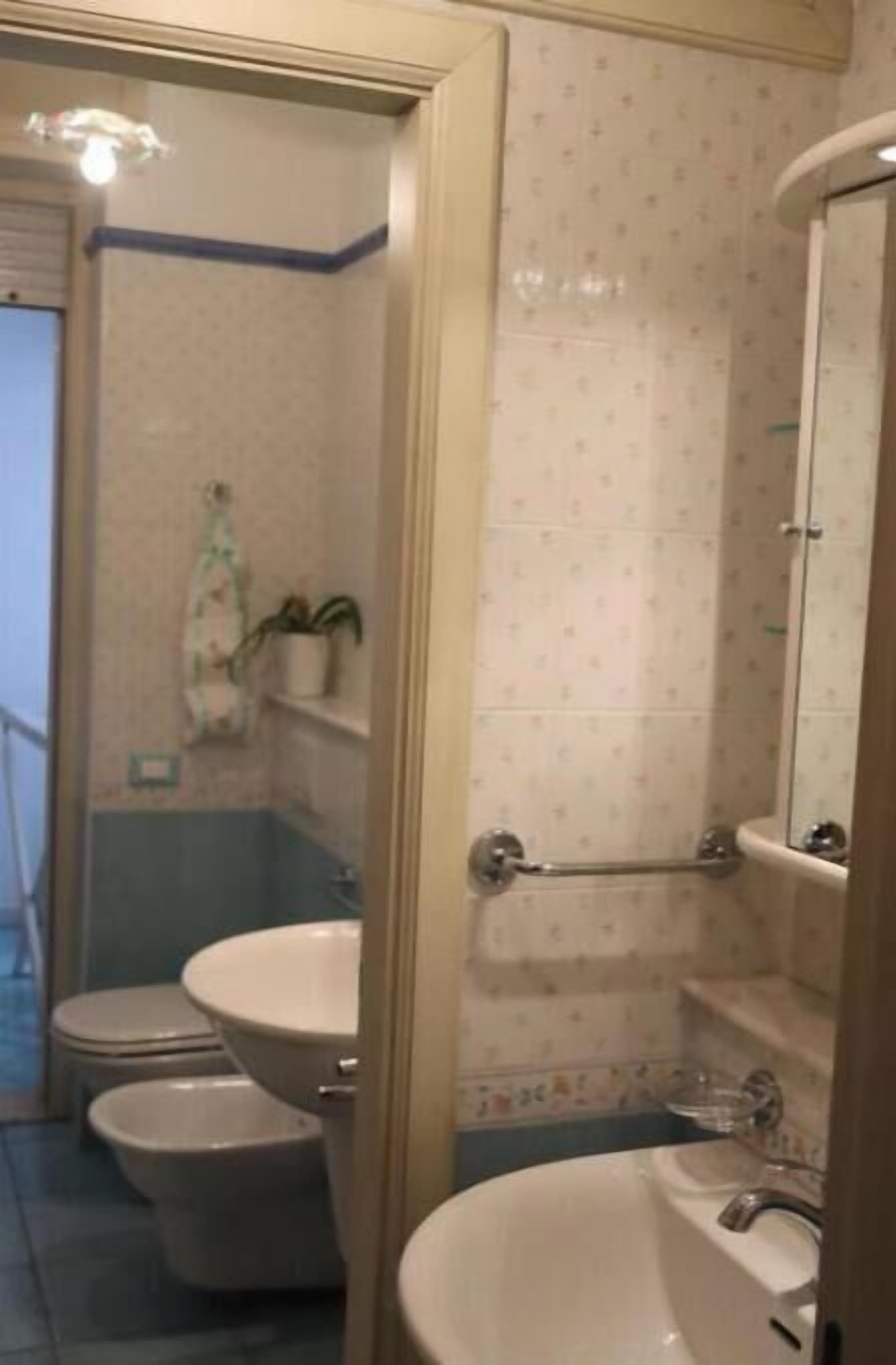 Un baño con dos inodoros, un lavabo, una ducha y un espejo.