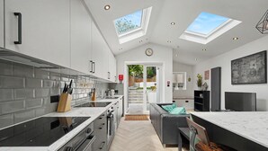 A modern kitchen with a skylight, a dining area with a bar, and a staircase leading to a garden. - Modern 5 bed New Cross Greenwich House (London)