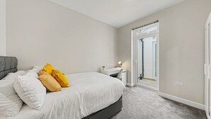 A bedroom with a bed, bedside table, and a desk. - Modern 5 bed New Cross Greenwich House (London)