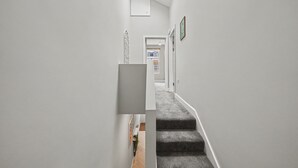 A narrow hallway with a carpeted staircase leading to a door. - Modern 5 bed New Cross Greenwich House (London)