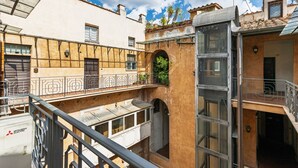 Une cour intérieure avec un bâtiment doté d’un balcon, d’une fenêtre offrant une vue et d’une porte.