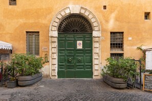 A building with a green double door, a sign prohibiting parking, and two large planters with greenery. - Luxury Loft in Navona - Anima (Rome)