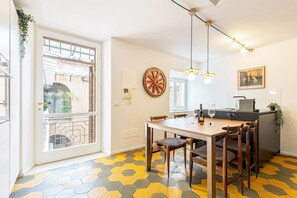 A dining area with a table, chairs, a decorative wheel, pendant lights, and a view through a glass door. - Luxury Loft in Navona - Anima (Rome)