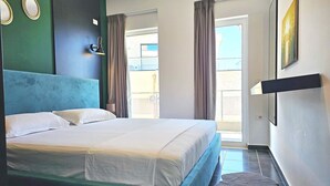 Et hotelværelse med en seng, en væglampe, et billede og udsigt gennem et vindue.