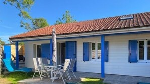 A house with a tiled roof, a covered patio with chairs and a table, and a small garden area. - Gîte Nath & Steph 5 classified 3*** in Cayeux sur Mer - Baie de Somme (Cayeux-sur-Mer)