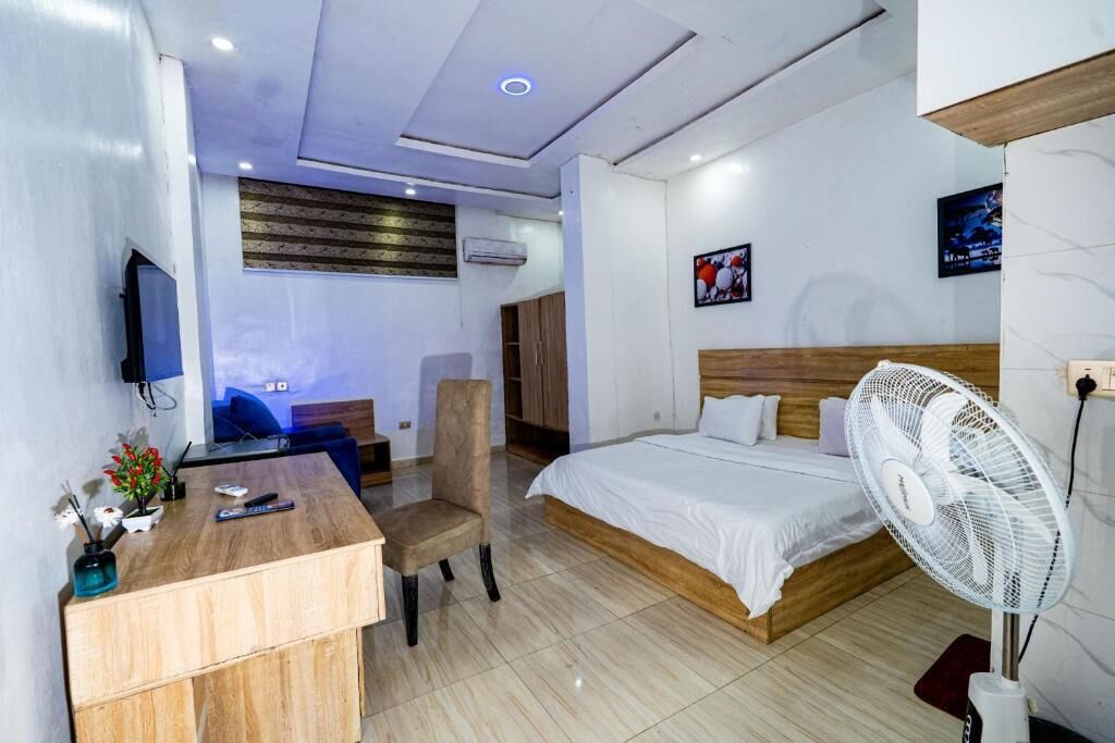 Une chambre d’hôtel équipée d’un lit, d’un bureau, d’une chaise, d’une télévision et d’un ventilateur.