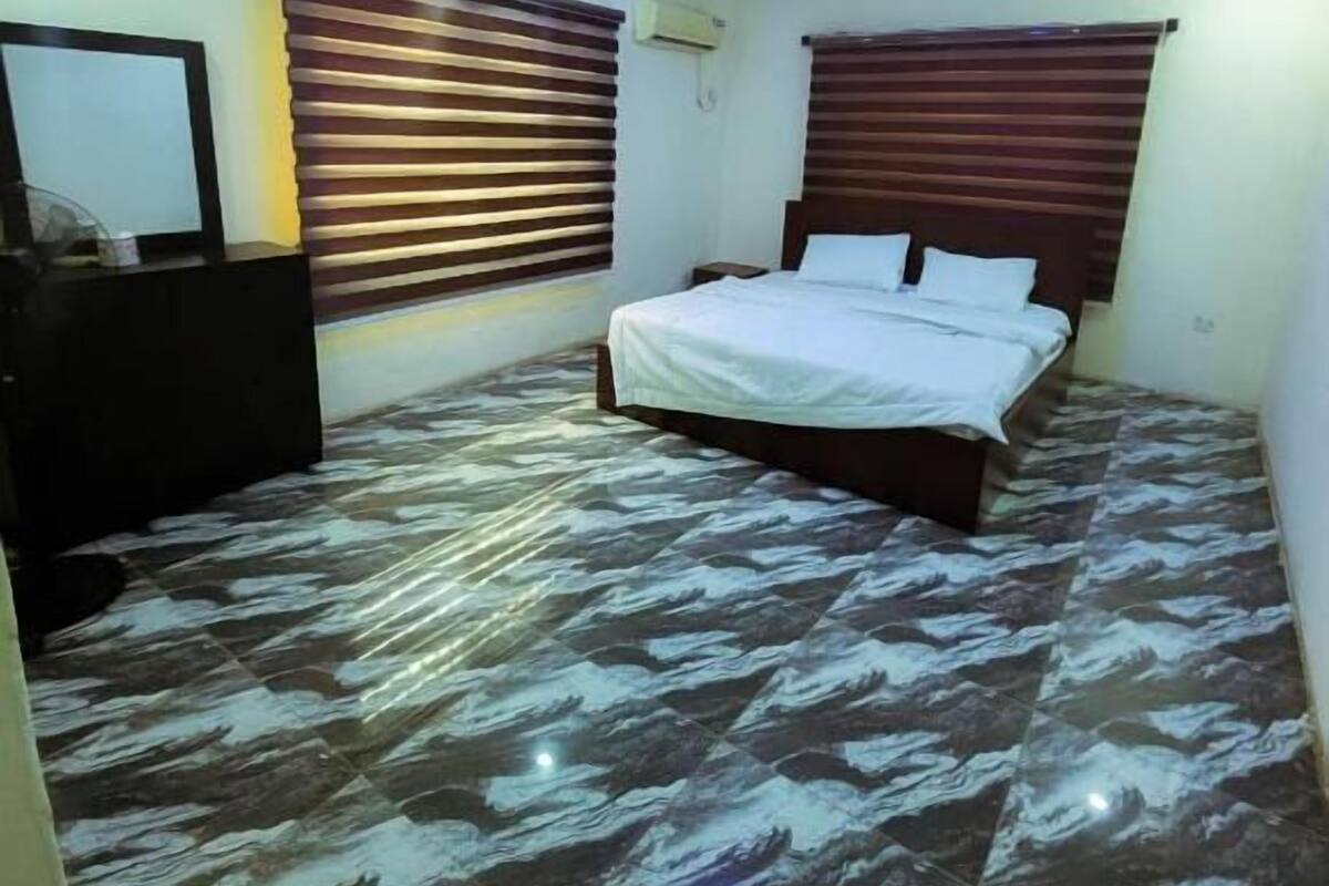 Un dormitorio con una cama, un aparador y una lámpara en el techo.