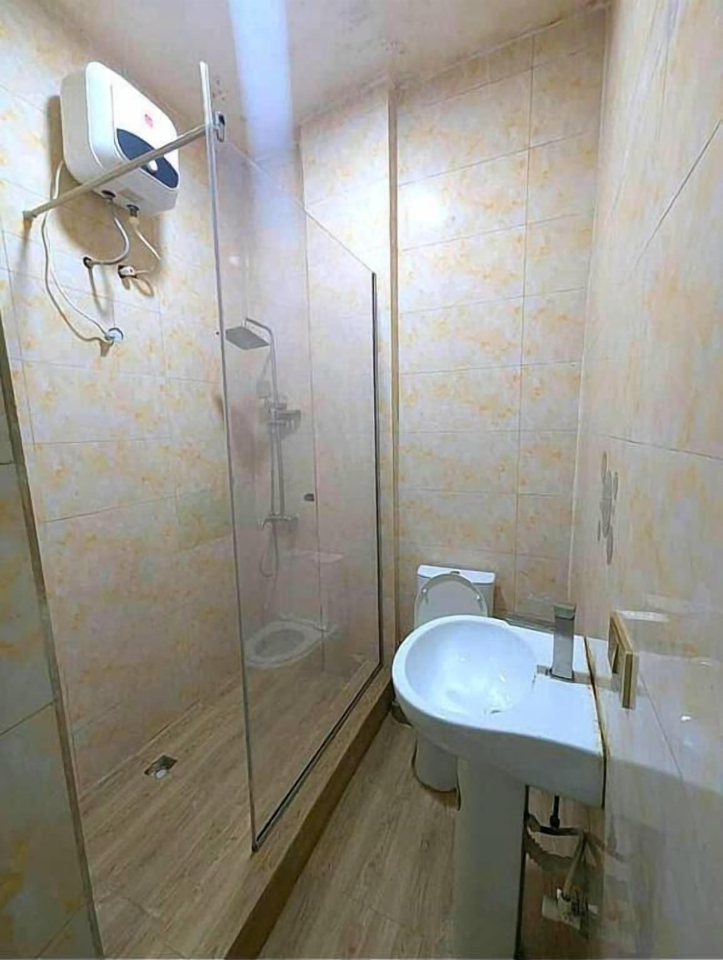 A bathroom with a glass-enclosed shower, a toilet, and a sink.