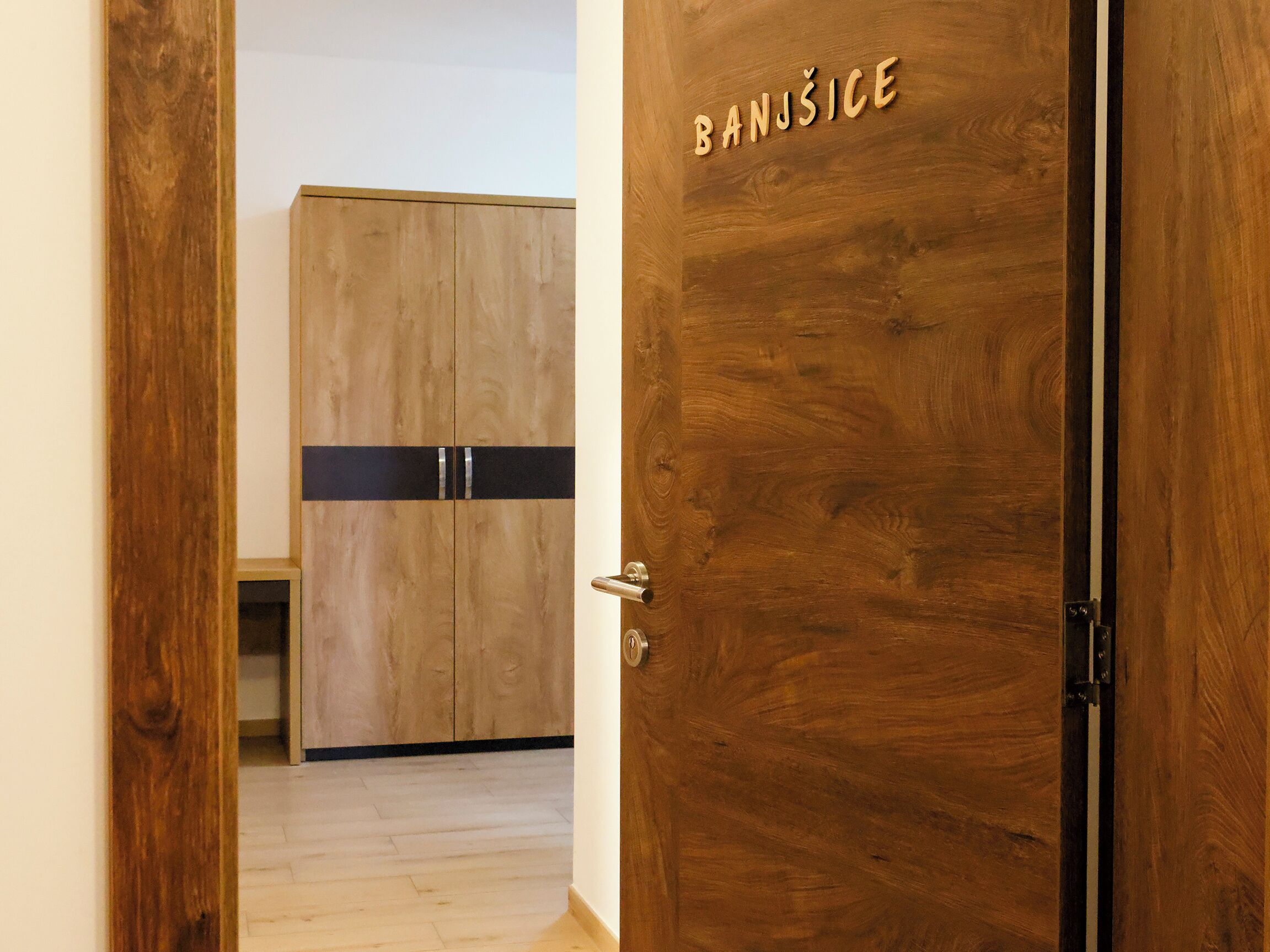 Una porta di legno con la scritta 'BANJŠICE' e un armadio con una striscia nera.
