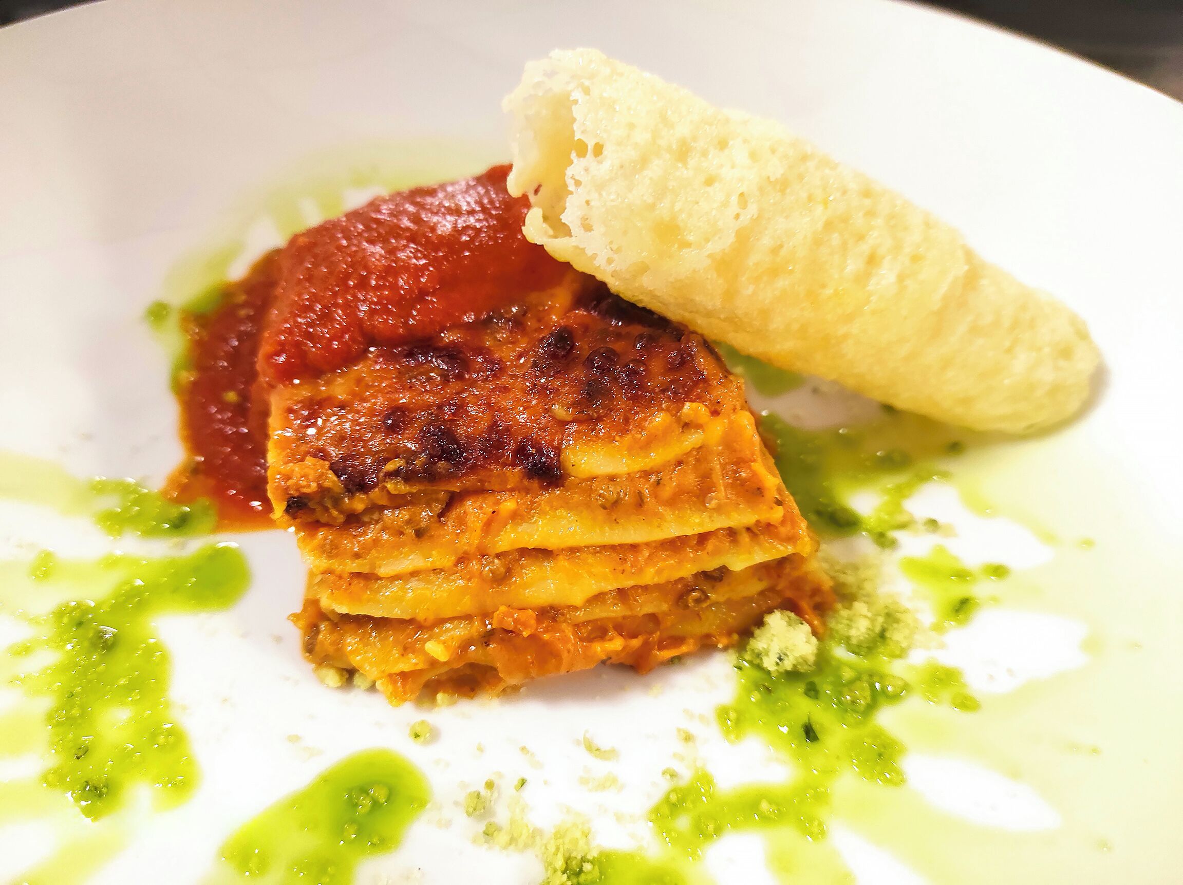A dessert with a layered pastry, a scoop of ice cream, and green sauce on a plate.