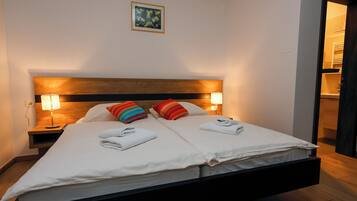 Ein modernes Hotelzimmer mit einem Bett, zwei Nachttischlampen, einem Holzkopfteil und einem kleinen Gemälde an der Wand.