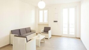 Un salon moderne comprenant un canapé, deux fauteuils, une table basse et une grande fenêtre offrant une belle vue.
