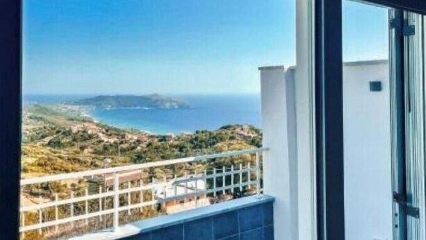 Un balcon avec vue sur la mer et les collines.