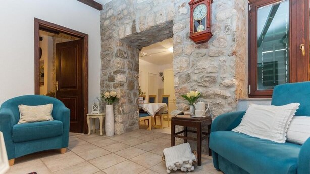Ein Wohnzimmer mit zwei blauen Sofas, einer Steinwand, einer Holztür und einer Uhr.