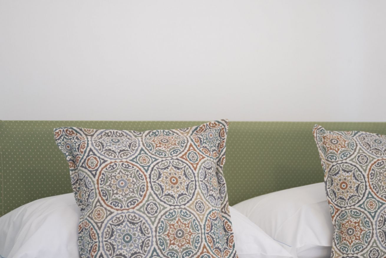 Ein Bett mit gemusterten Kissen und einem grünen Kopfteil.