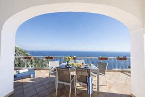 Una terrazza con un tavolo apparecchiato per due, con vista sulla costa.