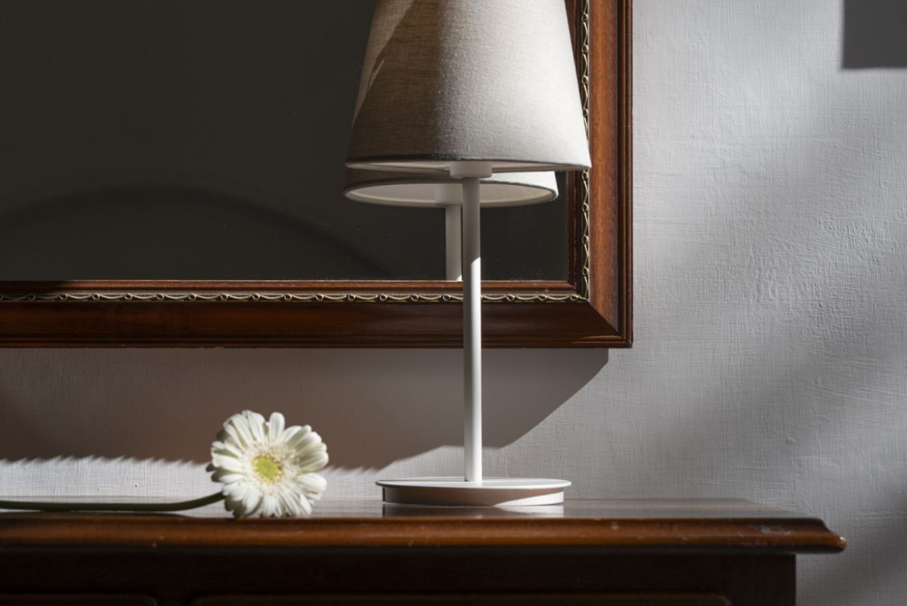 Una lampada su un tavolo con uno specchio sopra.