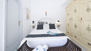 Un dormitorio con cama, mesitas de noche, un armario y una puerta.