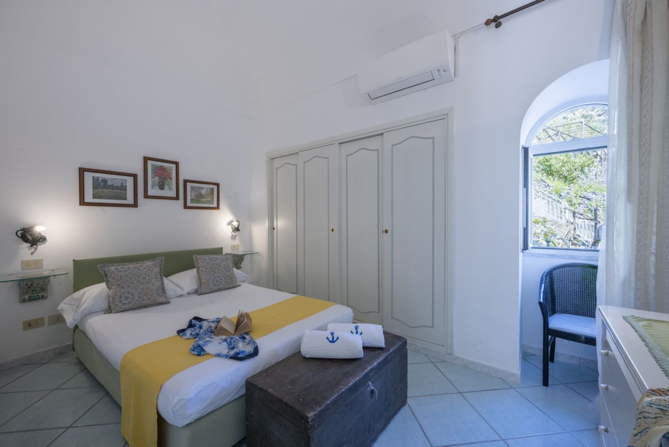 A bedroom with a bed, bedside tables, a wardrobe, a window, and a chair.