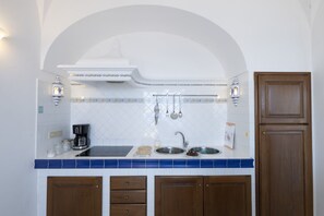 Eine Küche mit weiß gefliestem Fliesenspiegel, einer Edelstahlspüle, Holzschränken und einem eingebauten Backofen.